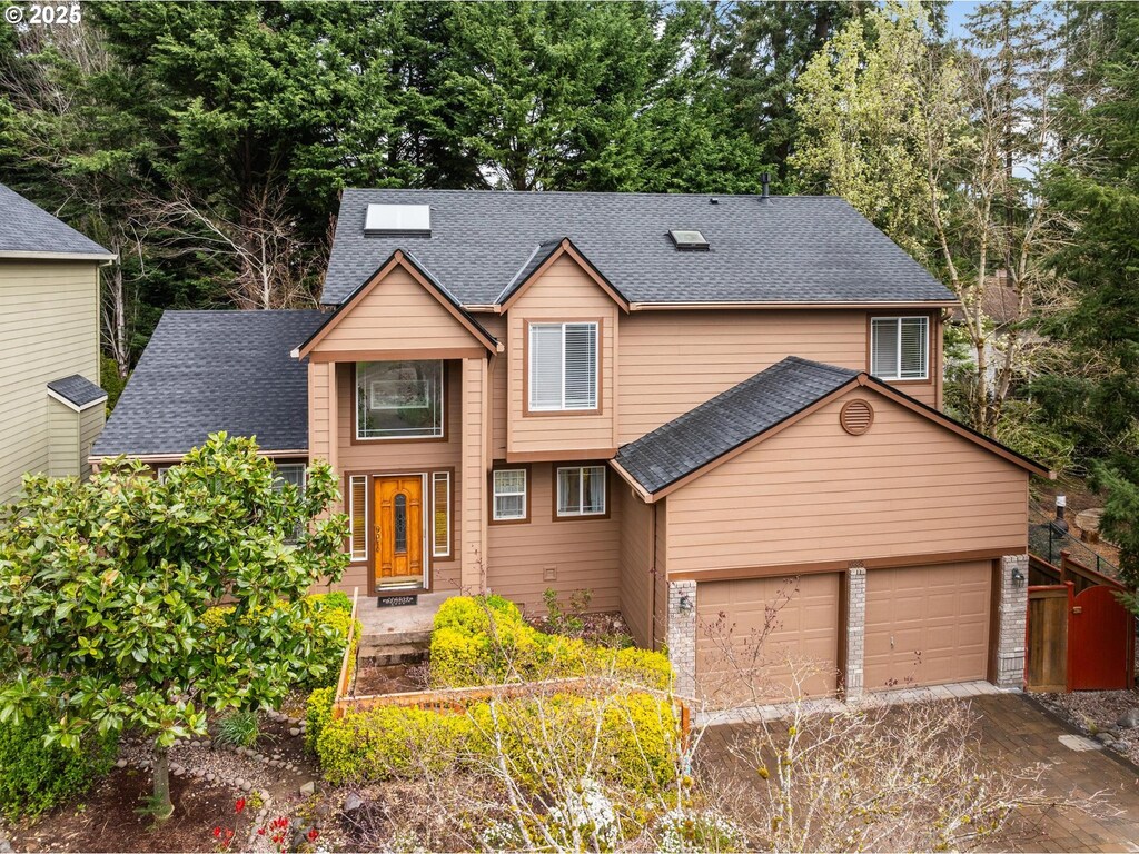 view of front of home featuring roof with shingles, driveway, and an attached garage