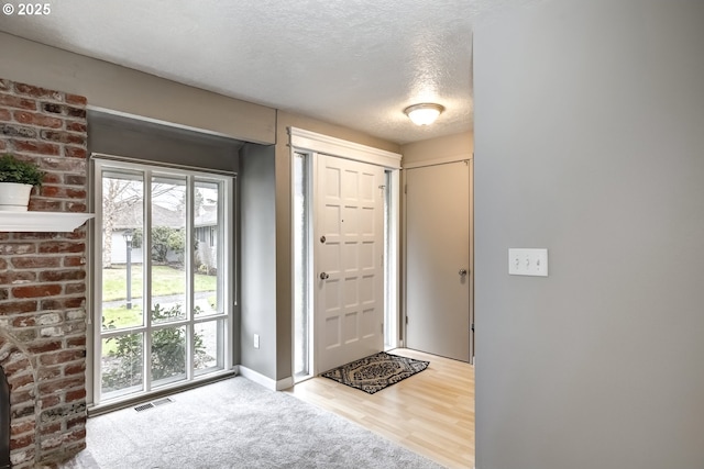 entryway with a healthy amount of sunlight, light carpet, and a textured ceiling