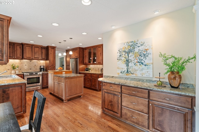 14230 Amberwood Cir, Lake Oswego, OR 97035 - kitchen featuring stainless steel appliances, a sink, light wood finished floors, light stone counters, and a kitchen island