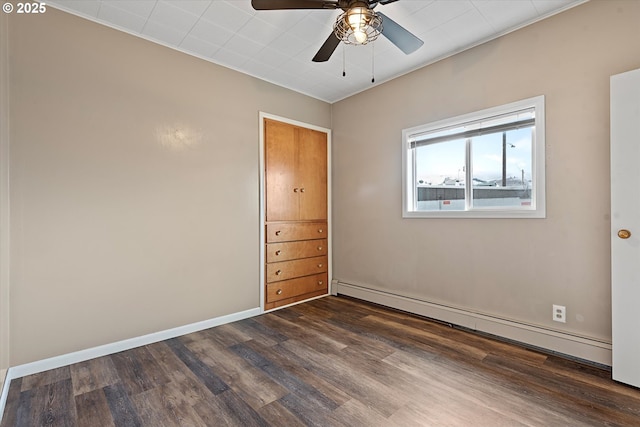 empty room with dark wood-type flooring, baseboards, baseboard heating, and a ceiling fan