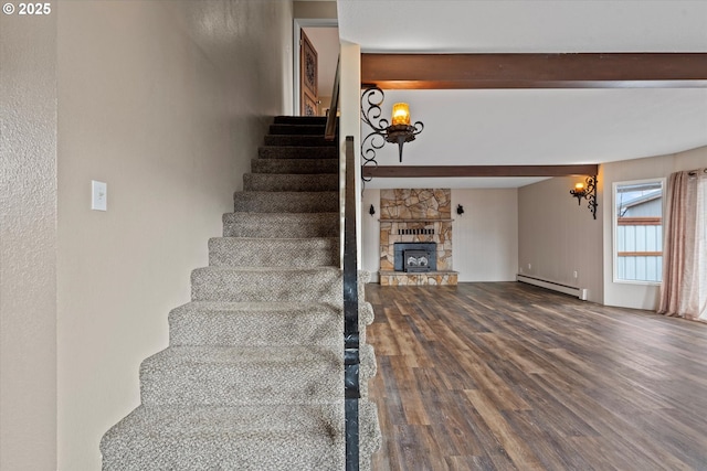 stairs with beam ceiling, a fireplace, baseboard heating, and wood finished floors