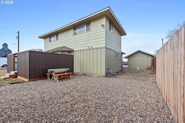 back of house featuring an outbuilding, a shed, and fence