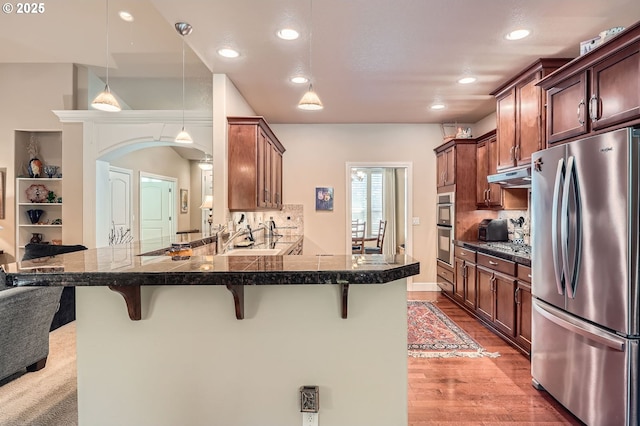 1114 S 6th Way, Ridgefield, WA 98642 - kitchen featuring stainless steel appliances, under cabinet range hood, a kitchen breakfast bar, tile countertops, and decorative backsplash