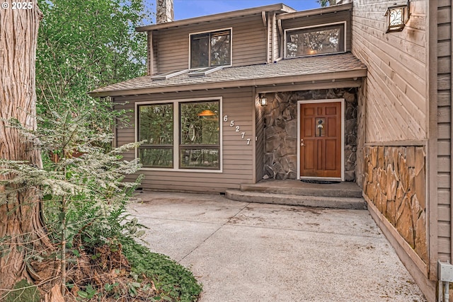 65277 E Sandy River Ln, Rhododendron, OR 97049 - property entrance with a chimney, a shingled roof, and a patio area