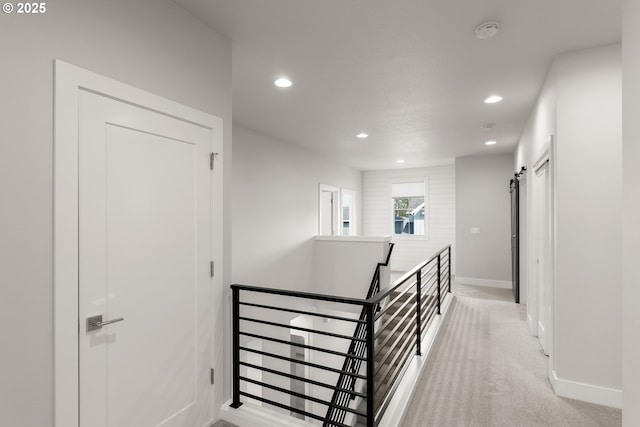 hall with light carpet and a barn door