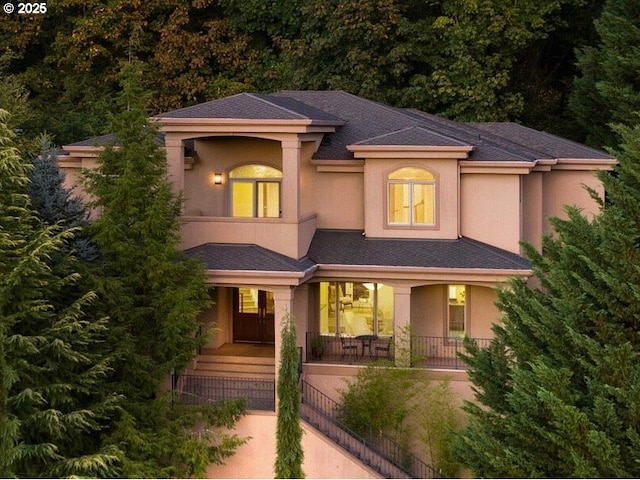 view of front of property featuring covered porch, roof with shingles, and stucco siding