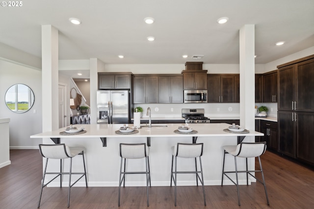 974 Legacy Ln, Eugene, OR 97402 - kitchen with stainless steel appliances, a kitchen island with sink, dark brown cabinetry, a kitchen bar, and light countertops
