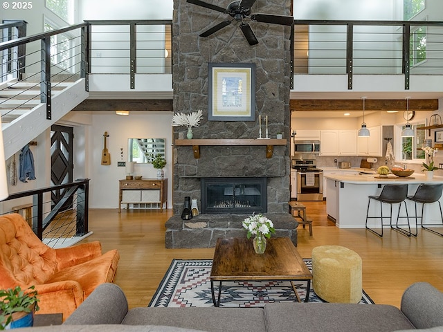 1339 NW 7th Ave, Camas, WA 98607 - living area featuring light wood-type flooring, a ceiling fan, a towering ceiling, a fireplace, and plenty of natural light