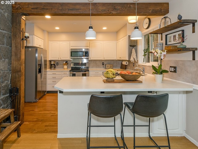 1339 NW 7th Ave, Camas, WA 98607 - kitchen featuring appliances with stainless steel finishes, a peninsula, light wood-type flooring, white cabinetry, and pendant lighting