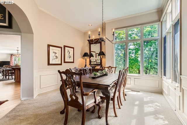 9122 NW Wood Rose Loop, Portland, OR 97229 - dining room with a chandelier, a decorative wall, light carpet, ornamental molding, and arched walkways