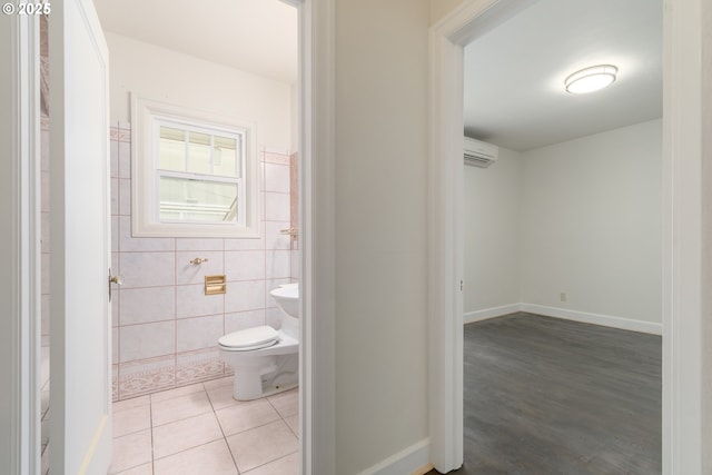 bathroom featuring toilet, a wall mounted air conditioner, tile walls, and tile patterned floors