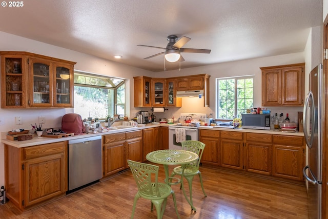 128 NW Woodrose Ct, Roseburg, OR 97471 - kitchen featuring appliances with stainless steel finishes, a sink, brown cabinetry, under cabinet range hood, and recessed lighting