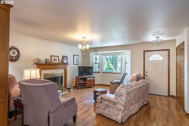 128 NW Woodrose Ct, Roseburg, OR 97471 - living area featuring wood finished floors, a tiled fireplace, a chandelier, and baseboards