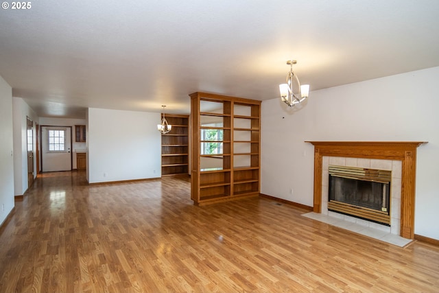 128 NW Woodrose Ct, Roseburg, OR 97471 - unfurnished living room with a chandelier, light wood-style floors, and a tiled fireplace