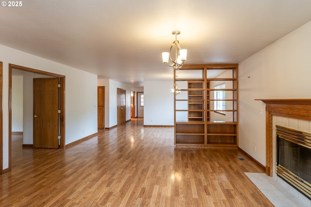 128 NW Woodrose Ct, Roseburg, OR 97471 - unfurnished living room featuring light wood finished floors, a tiled fireplace, and a chandelier