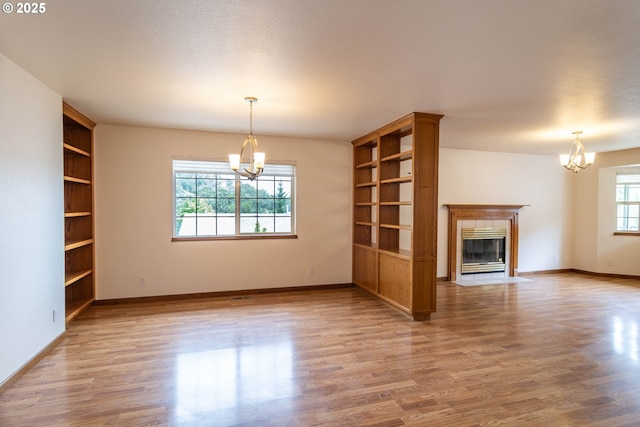 128 NW Woodrose Ct, Roseburg, OR 97471 - unfurnished living room with a chandelier, built in features, and wood finished floors