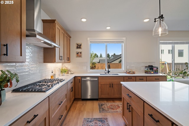 kitchen featuring appliances with stainless steel finishes, plenty of natural light, a sink, and wall chimney exhaust hood