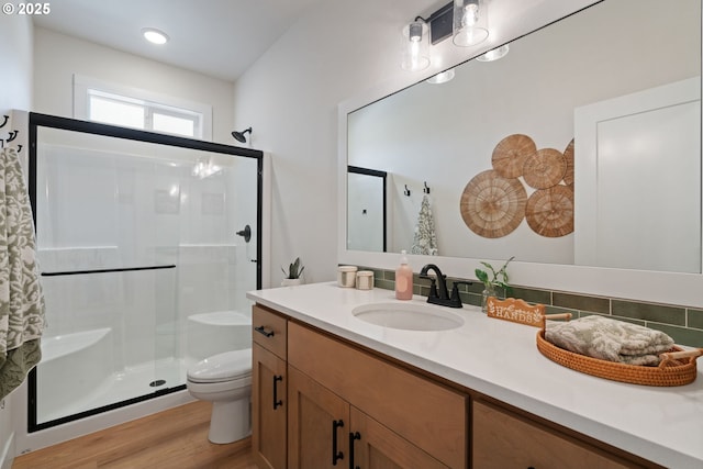 bathroom with vanity, a stall shower, toilet, and wood finished floors