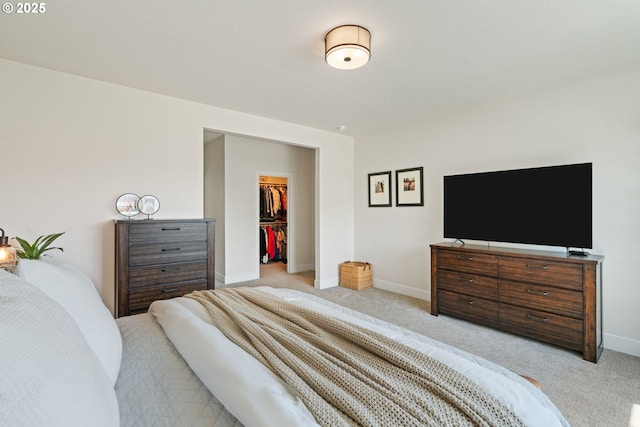 bedroom with baseboards, light carpet, and a spacious closet