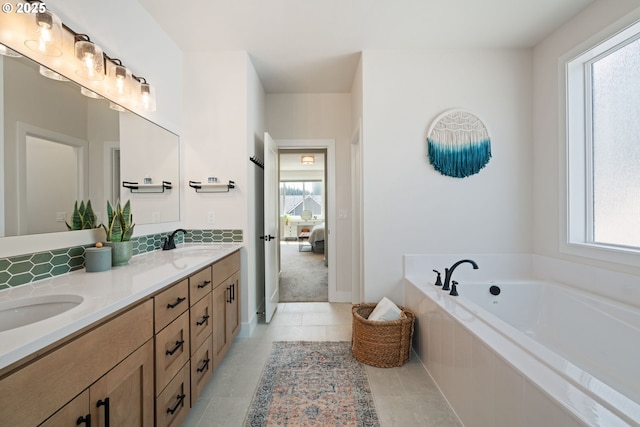 ensuite bathroom with a sink, a bath, double vanity, and connected bathroom