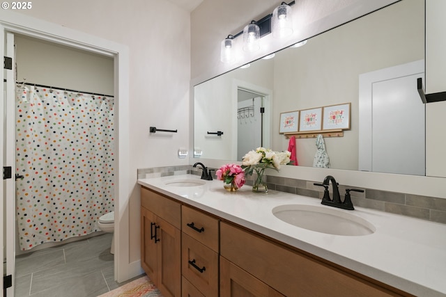 bathroom with double vanity, toilet, tile patterned floors, and a sink