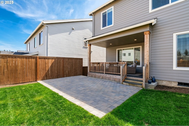 back of property featuring a lawn, fence, and a patio