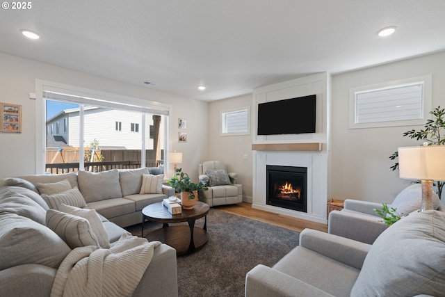 living room with recessed lighting, visible vents, a large fireplace, and wood finished floors