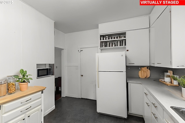 560 N 10th St, Coos Bay, OR 97420 - kitchen with freestanding refrigerator, light countertops, white cabinetry, concrete flooring, and black microwave