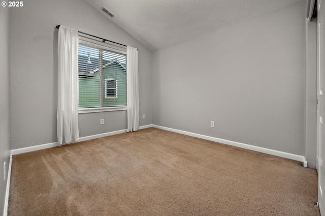 empty room featuring light carpet, vaulted ceiling, visible vents, and baseboards