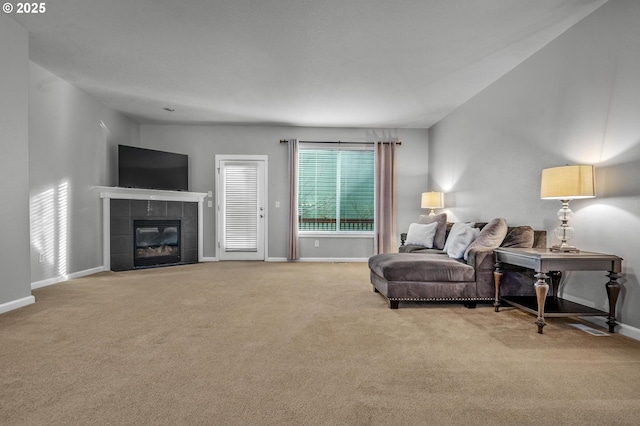 living room featuring baseboards, light carpet, and a tiled fireplace