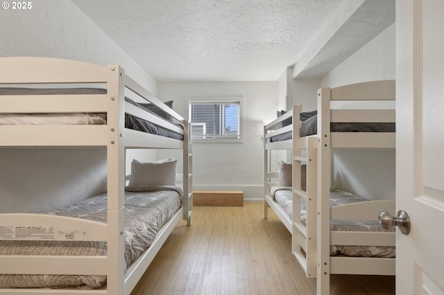 bedroom with baseboards, a textured ceiling, and wood finished floors