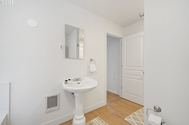 bathroom with heating unit, wood finished floors, and baseboards