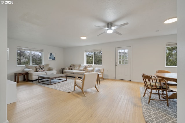 living room with light wood-style flooring, baseboards, a healthy amount of sunlight, and ceiling fan