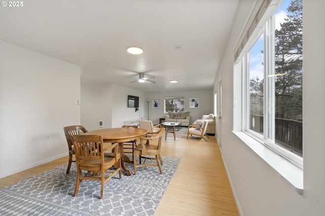 dining room with baseboards, a ceiling fan, and light wood finished floors