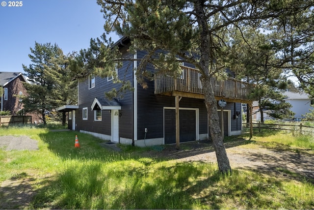 rear view of property with an attached garage, fence, and dirt driveway