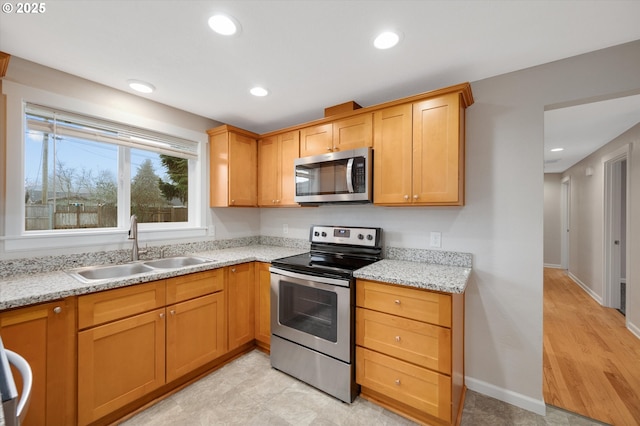 kitchen with light stone counters, sink, and stainless steel appliances