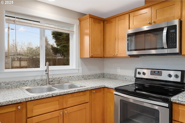 kitchen with appliances with stainless steel finishes, sink, and light stone counters