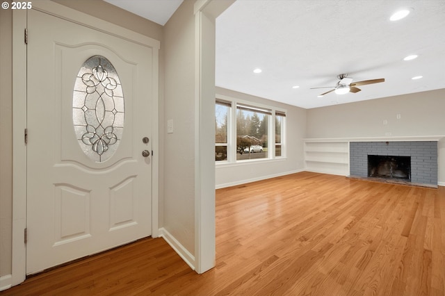 entrance foyer featuring ceiling fan, a fireplace, and light hardwood / wood-style flooring