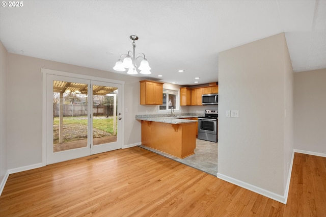 kitchen with a kitchen bar, sink, light hardwood / wood-style flooring, kitchen peninsula, and stainless steel appliances