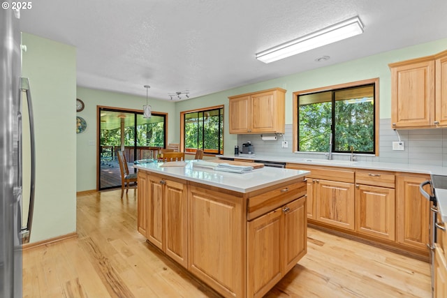 kitchen featuring tasteful backsplash, light countertops, light wood-type flooring, and a textured ceiling