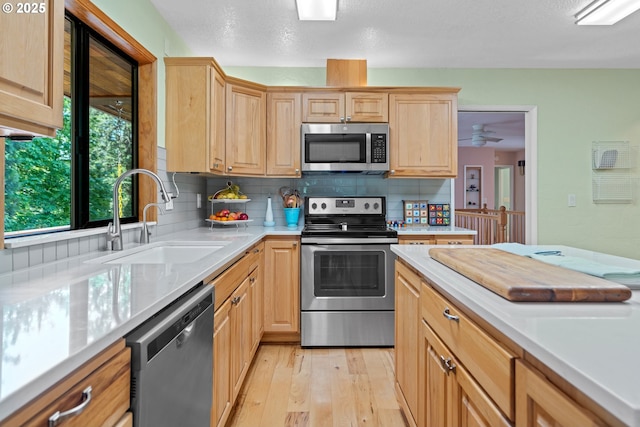 kitchen featuring stainless steel appliances, a sink, light brown cabinetry, and light countertops