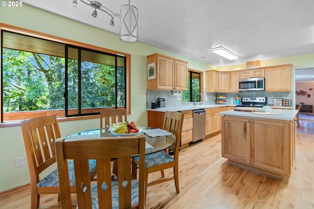 kitchen featuring stainless steel appliances, light brown cabinetry, light countertops, and light wood-type flooring