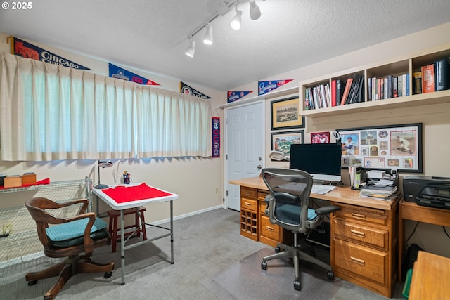 carpeted office space featuring rail lighting, a textured ceiling, and baseboards