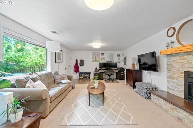 living area with a textured ceiling, a desk, carpet flooring, and a fireplace