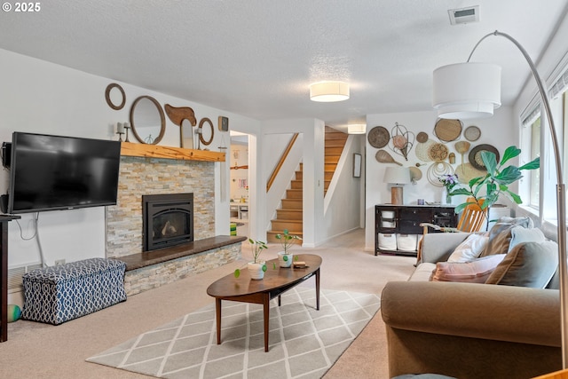 carpeted living room featuring stairway, a textured ceiling, and a stone fireplace