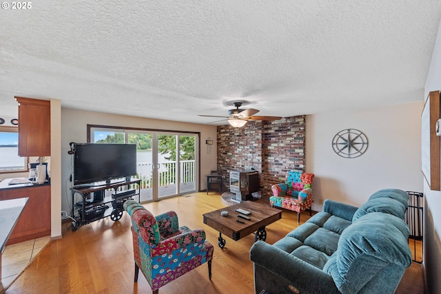 94020 E Shore Dr, North Bend, OR 97459 - living area with a textured ceiling, light wood-style floors, a ceiling fan, and a wood stove