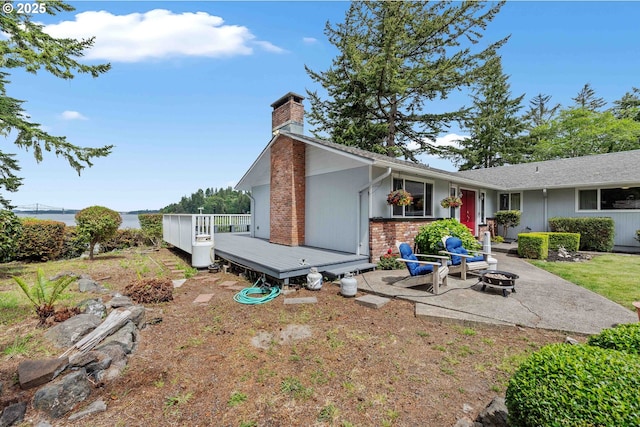 94020 E Shore Dr, North Bend, OR 97459 - back of house featuring a fire pit, a deck, a chimney, a patio area, and brick siding