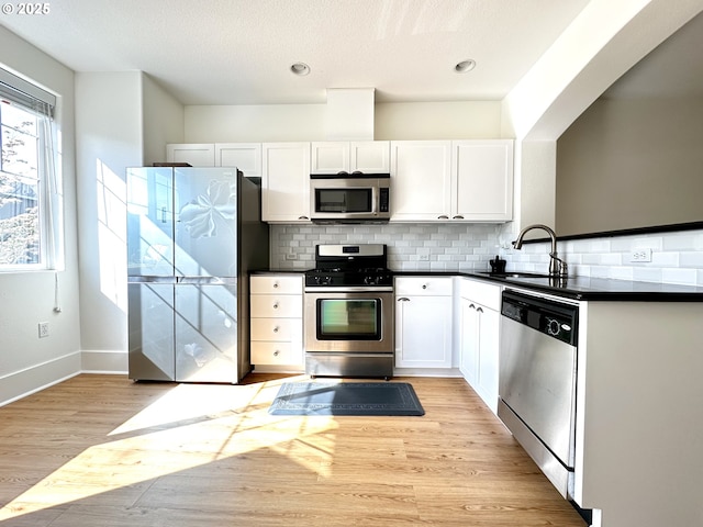 836 NW 118th Ave Unit 104, Portland, OR 97229 - kitchen featuring stainless steel appliances, dark countertops, a sink, white cabinetry, and recessed lighting