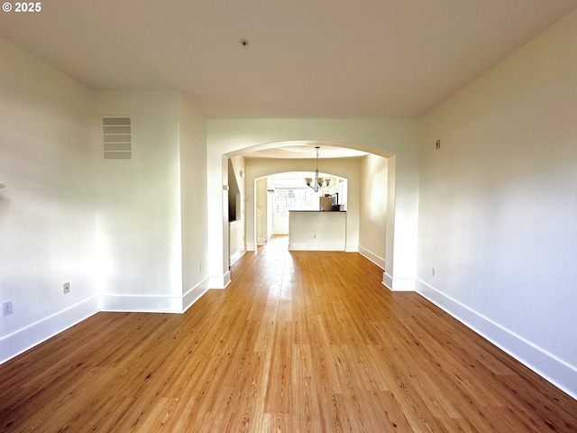 836 NW 118th Ave Unit 104, Portland, OR 97229 - interior space featuring visible vents, arched walkways, wood finished floors, baseboards, and an inviting chandelier