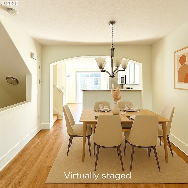 836 NW 118th Ave Unit 104, Portland, OR 97229 - dining area featuring a chandelier, arched walkways, light wood-style floors, stairway, and baseboards